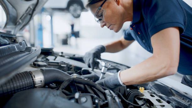 Mechanic repairing car engine in auto repair shop.