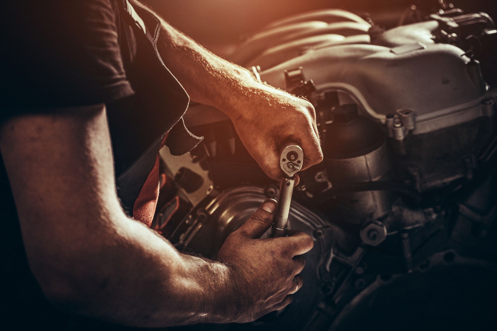 A man is working on a car engine with a wrench.