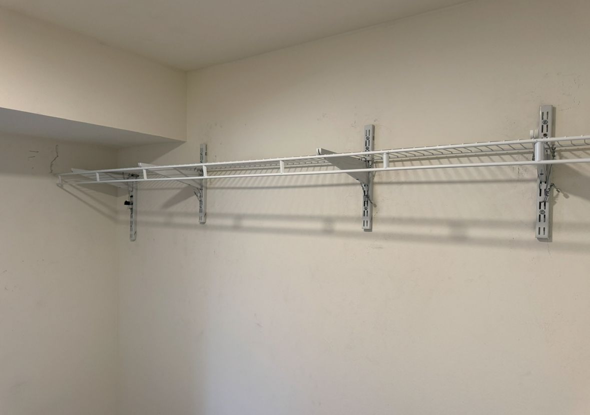 White wall with two black shelves above a countertop, next to a white cabinet and a window. Kitchen located in Norwalk Connecticut.