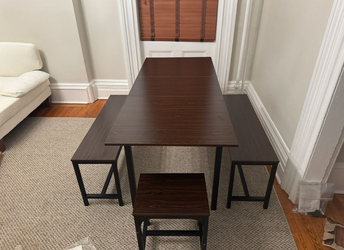 Dining table with two benches and a stool in front of a window. Dark brown furniture on a light-colored rug. Furniture assembly located in Connecticut.