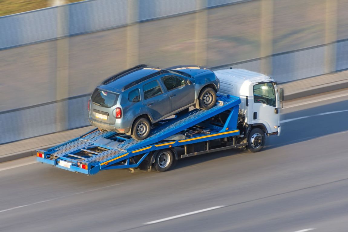 A tow truck is carrying a car on the back of it.