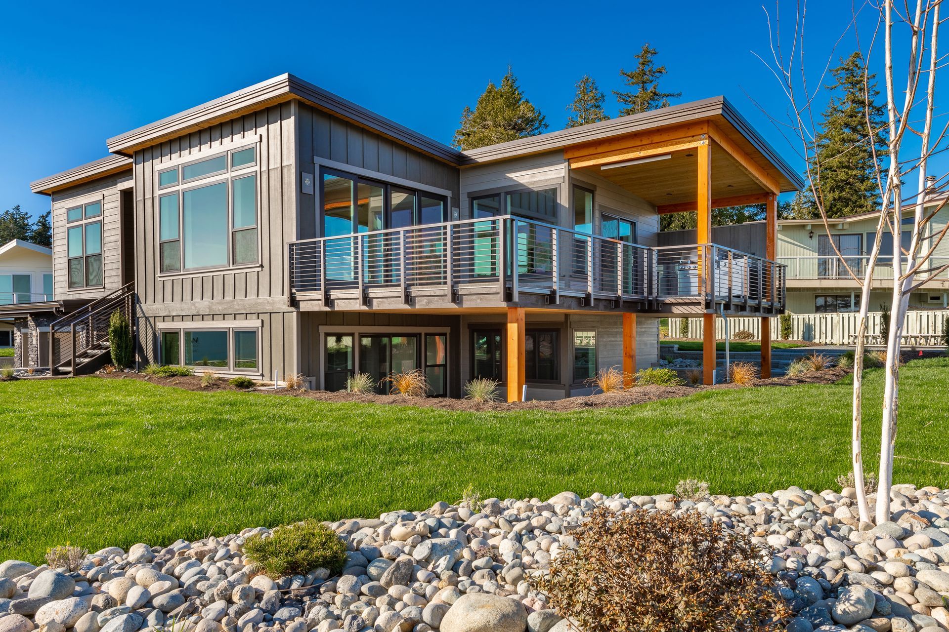 A large house with a lot of windows is sitting on top of a lush green field.