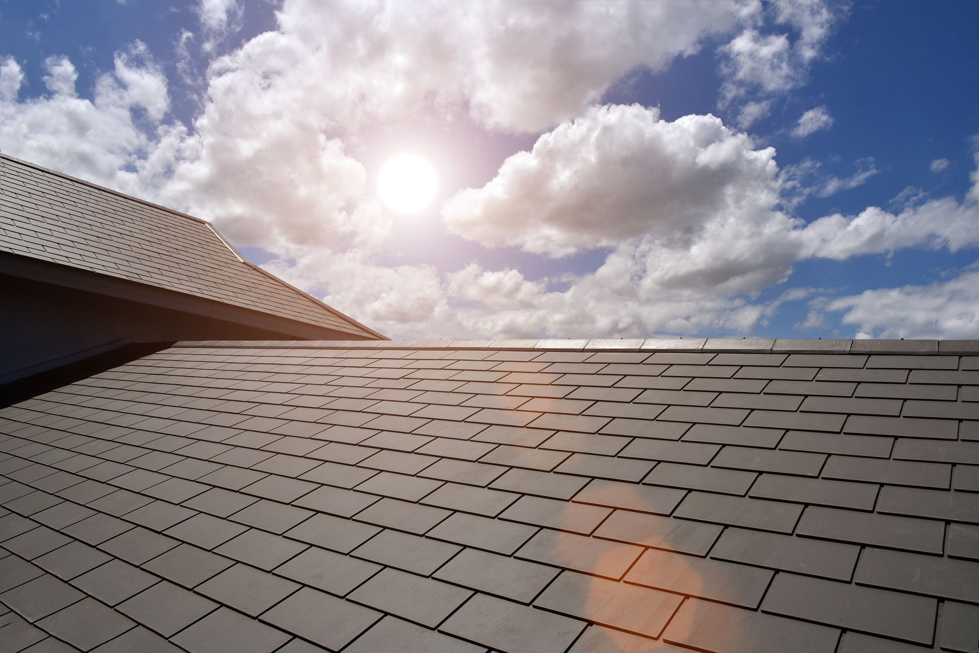 The sun is shining through the clouds on the roof of a house.