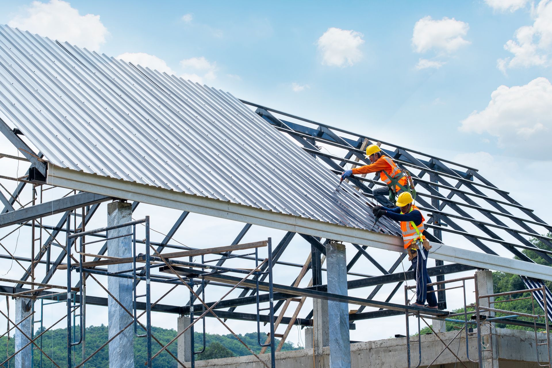 A group of construction workers are working on a metal roof.