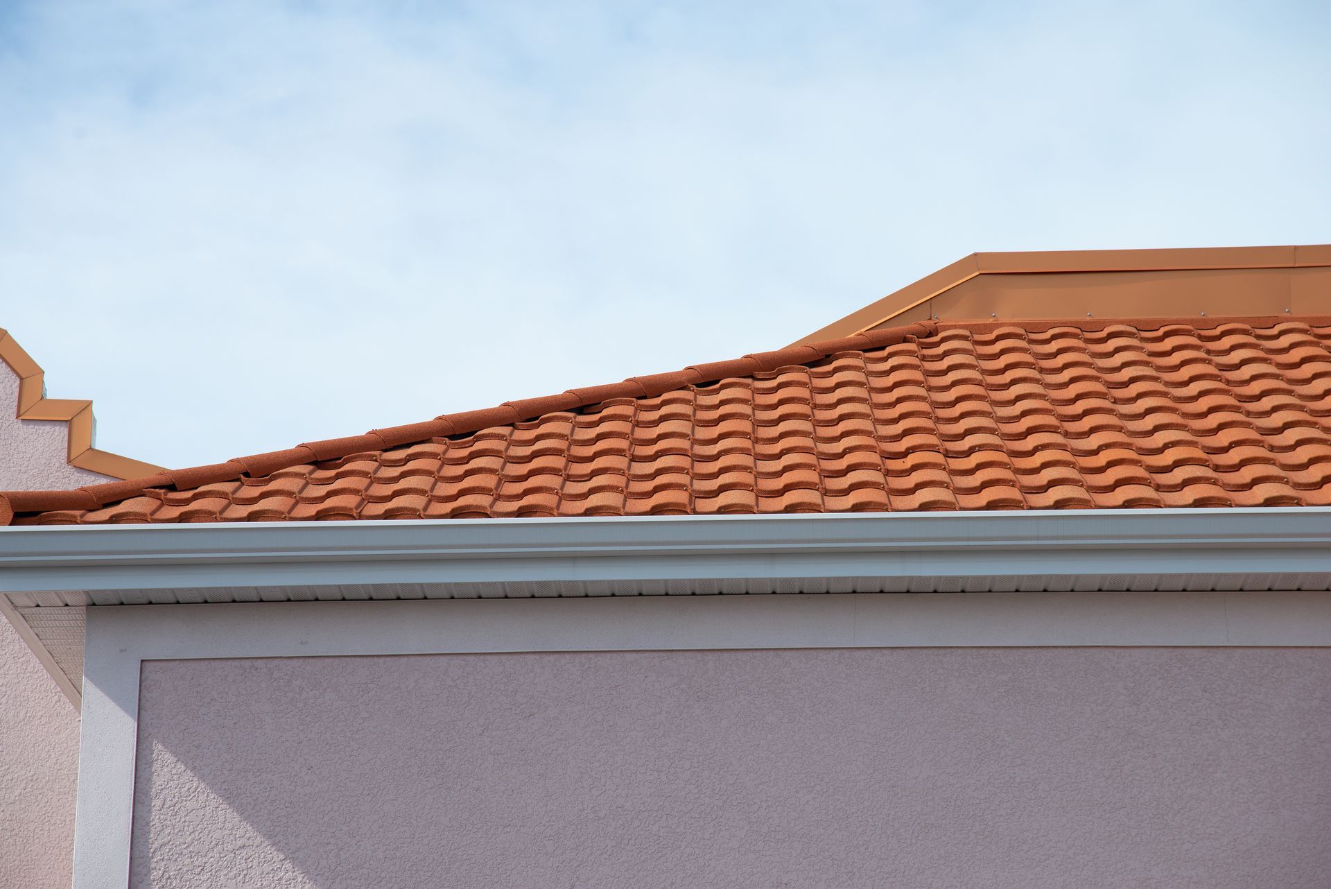 A house with a red tiled roof and a white gutter