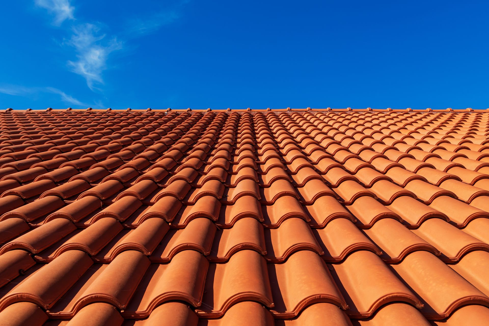 Looking up at a tiled roof with a blue sky in the background.