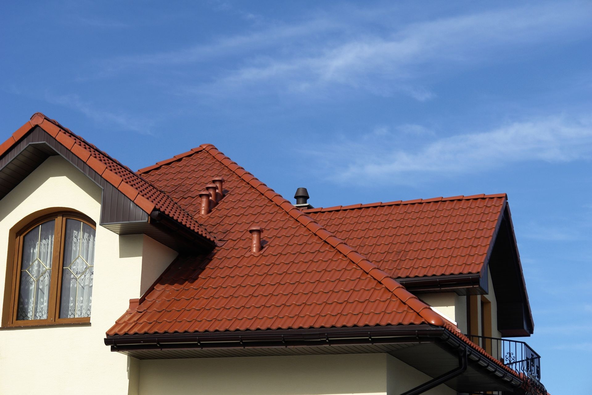 A house with a red tiled roof and a blue sky in the background.