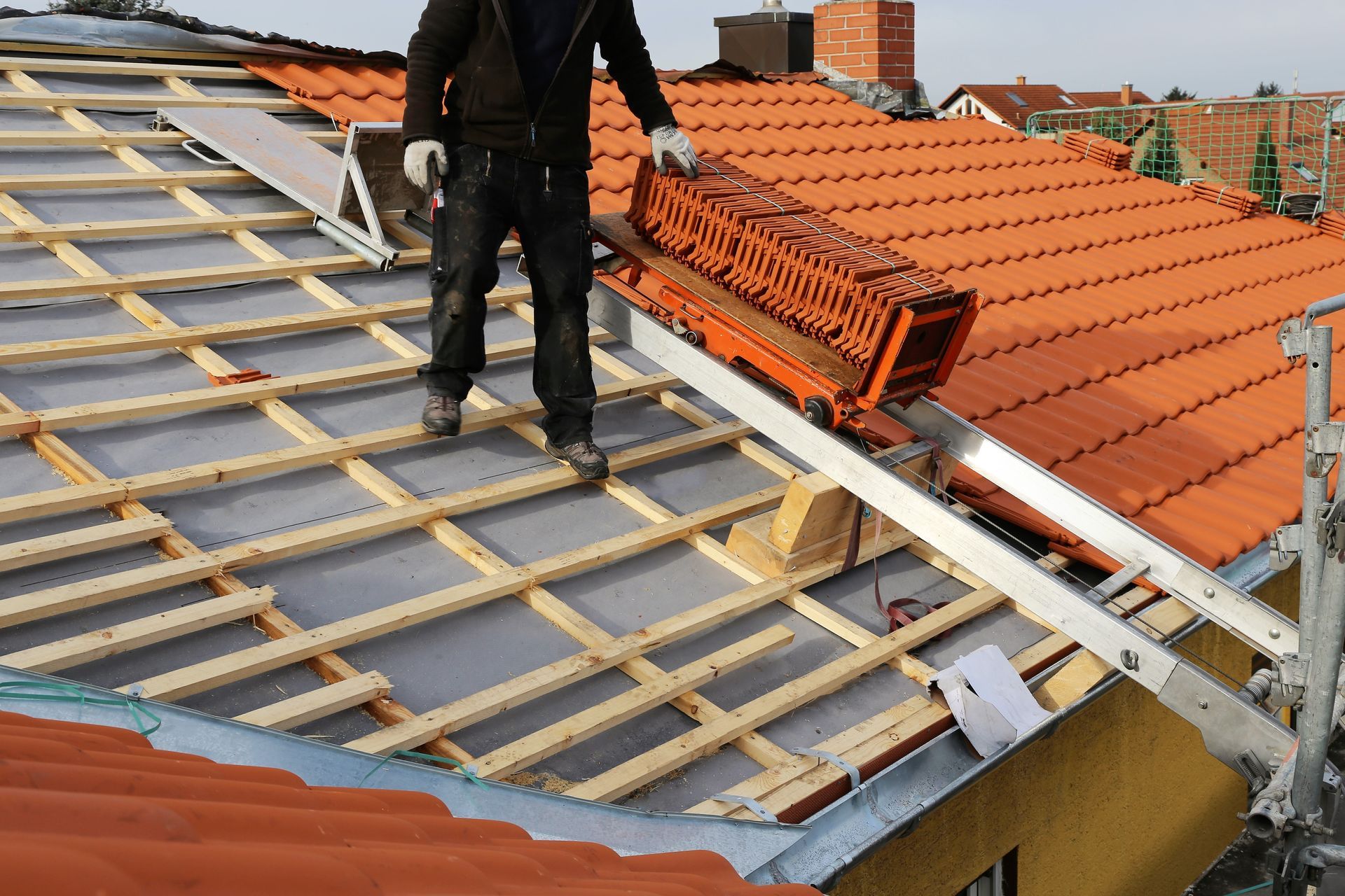 A man is standing on top of a tiled roof.