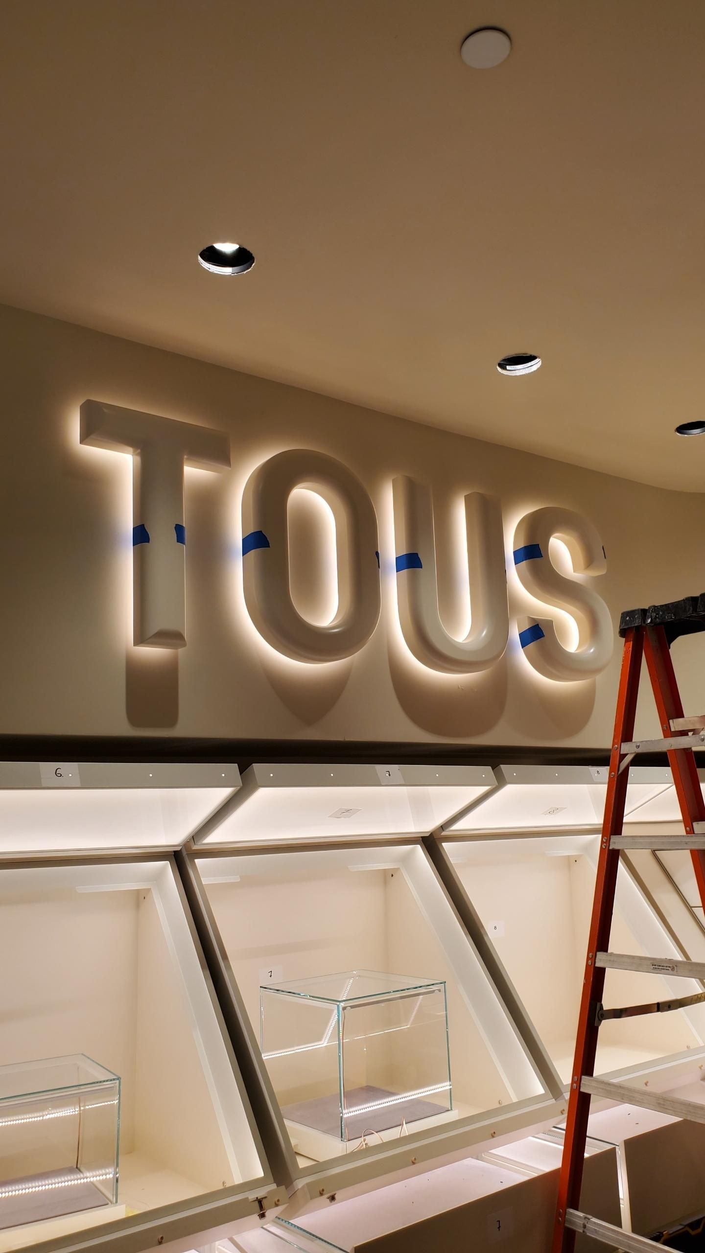 A tous sign is being installed in a store.