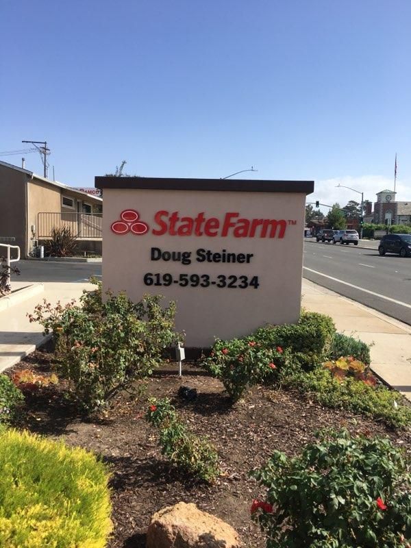 A state farm sign is sitting in the middle of a garden.