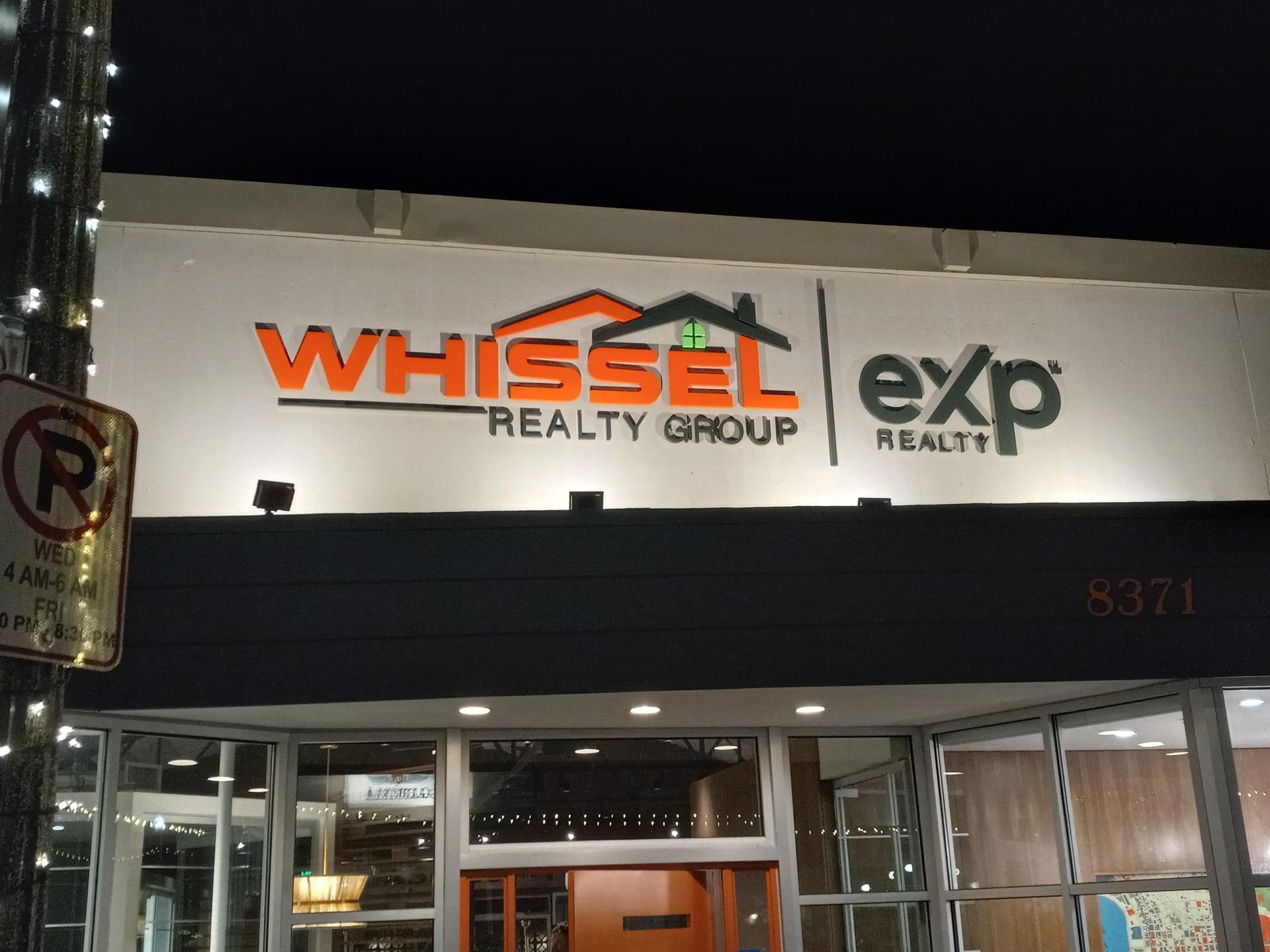 A sign for whissel realty group is lit up at night