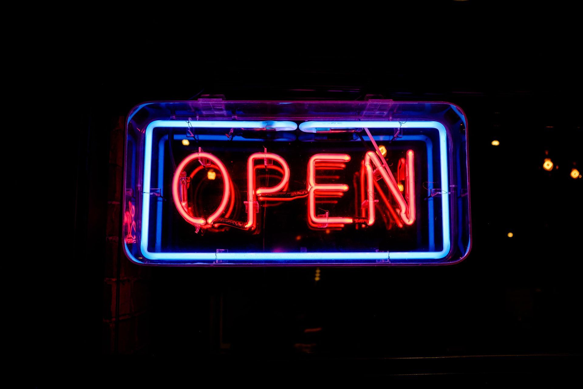 A neon sign that says `` open '' is lit up in the dark.