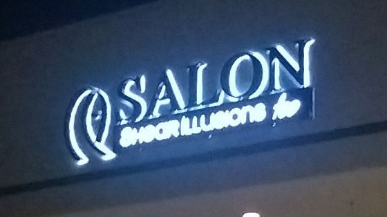 A salon sign that is lit up at night
