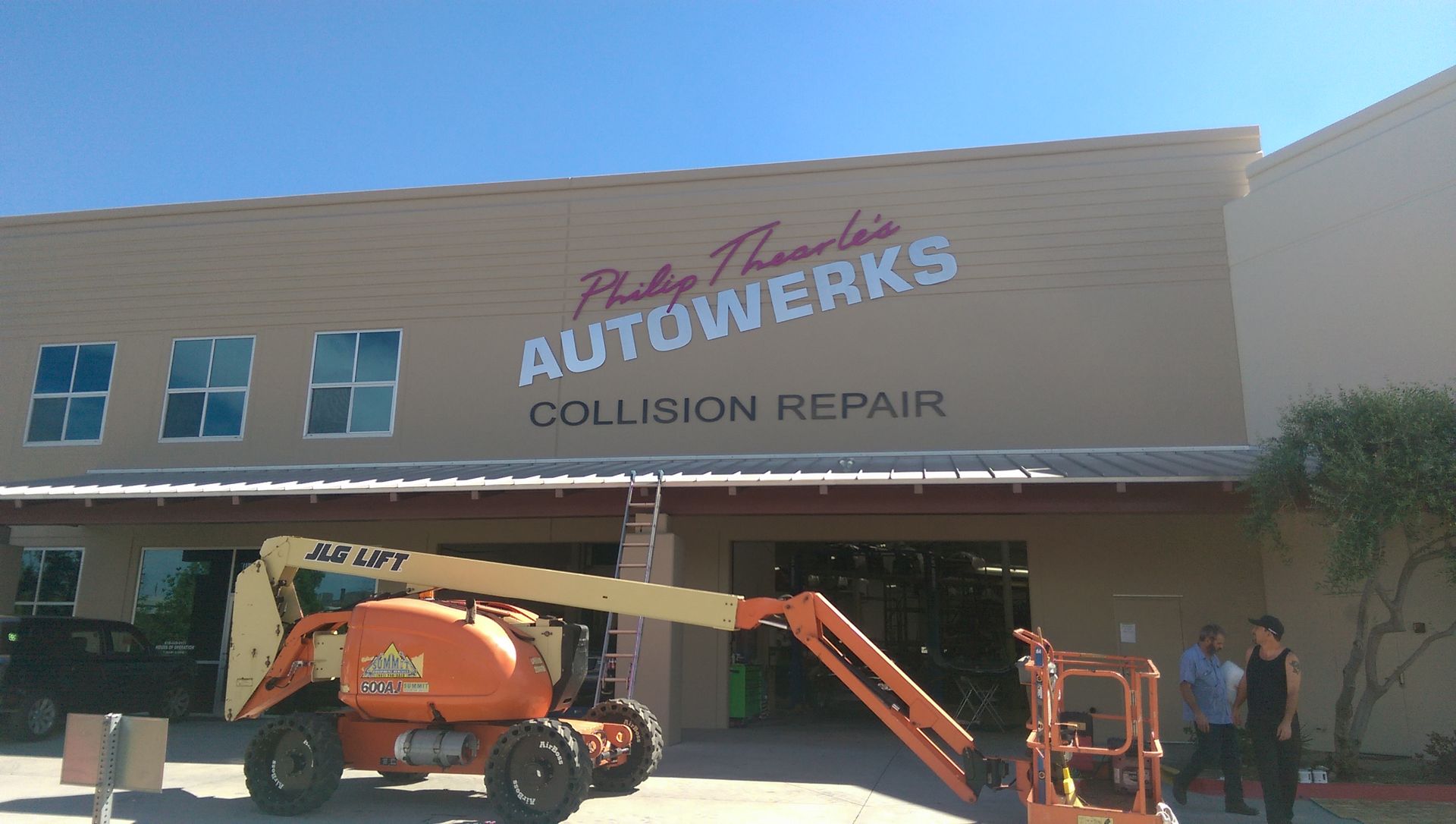 A collision repair shop with a jlg lift in front of it