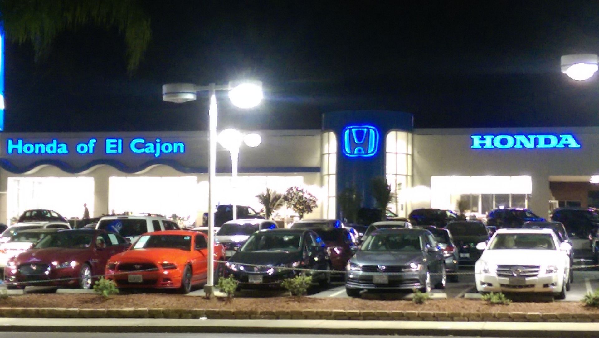 A row of cars are parked in front of a honda dealership