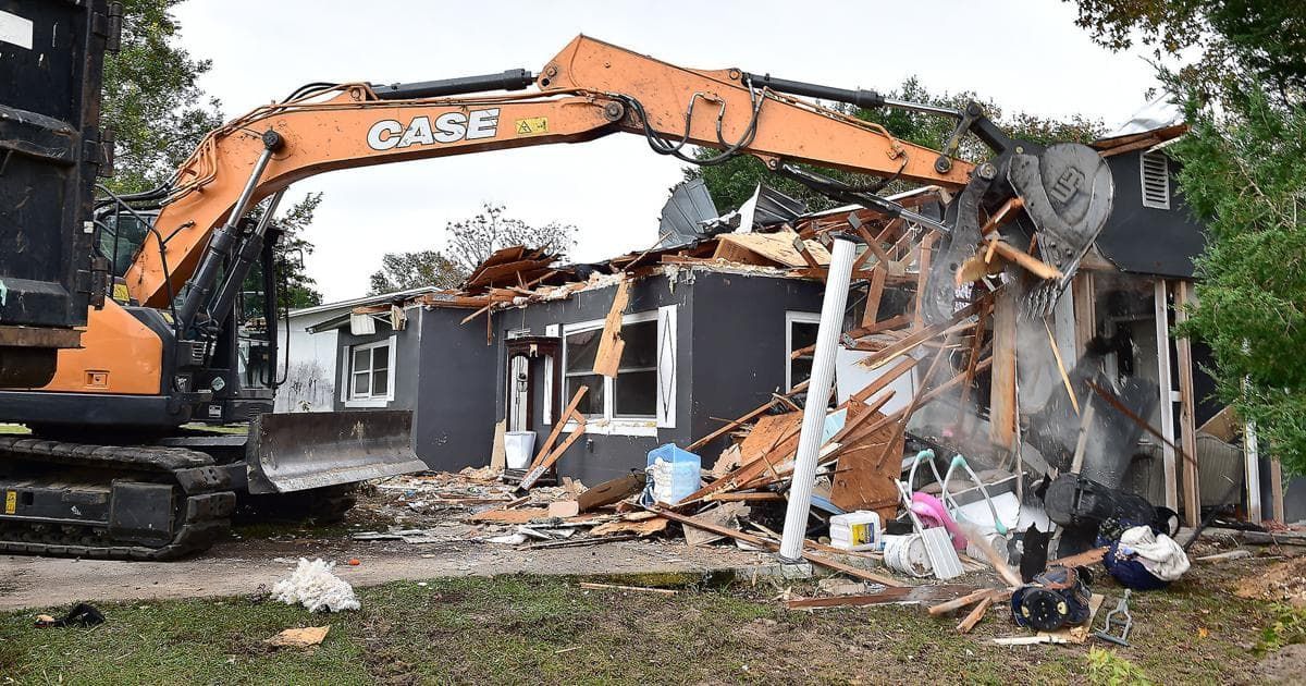 A demolition service company in Tuscaloosa, Alabama tearing down a residential home with an excavator.