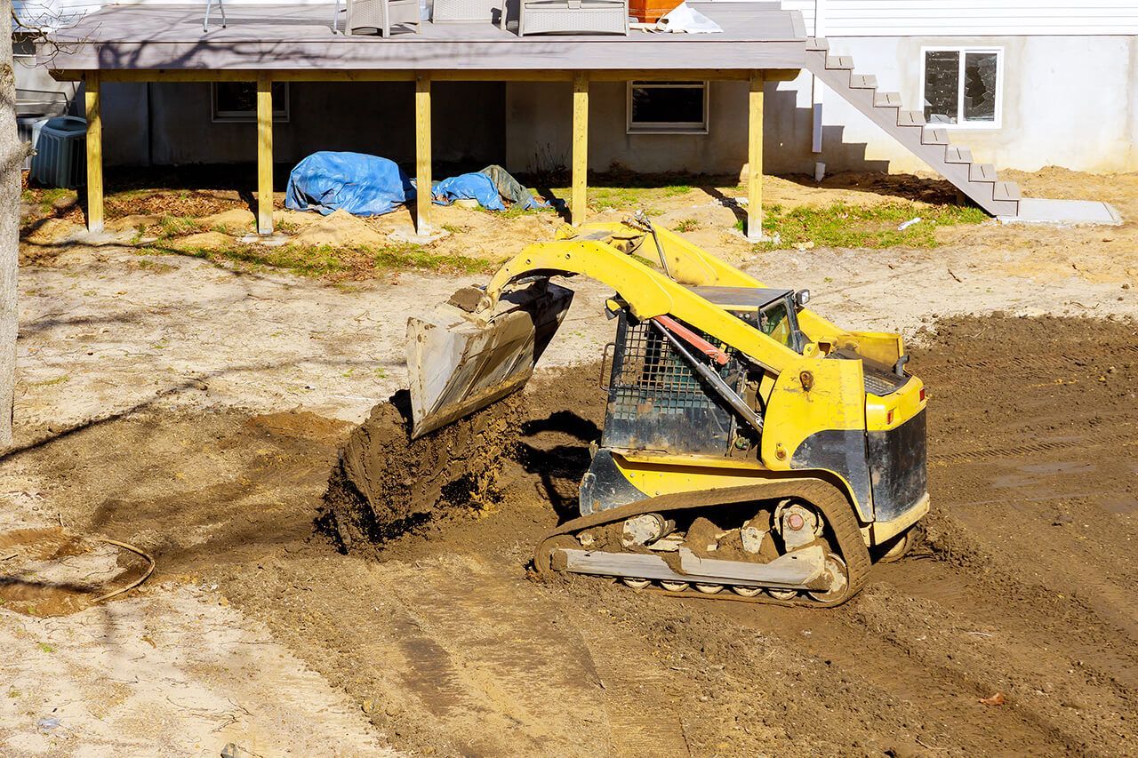 A Northport, Alabama excavating service company moving dirt with a  track loader in a residential yard.