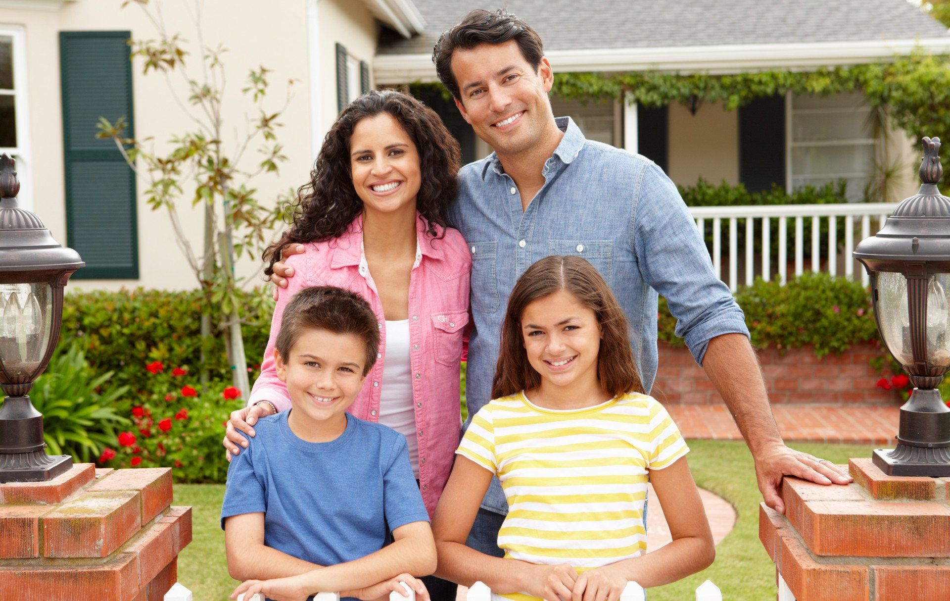 A family is posing for a picture in front of their house.