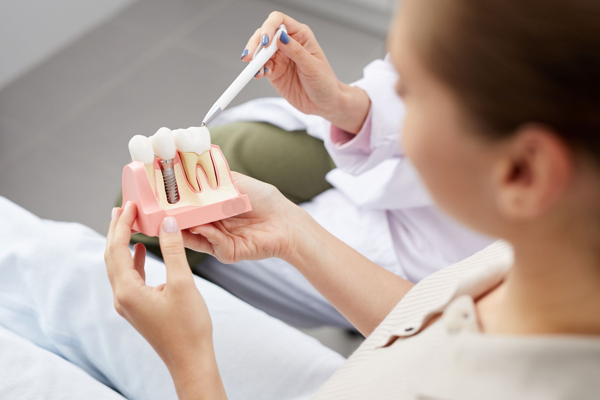 Person holding a dental model while pointing with a pen during an oral care consultation