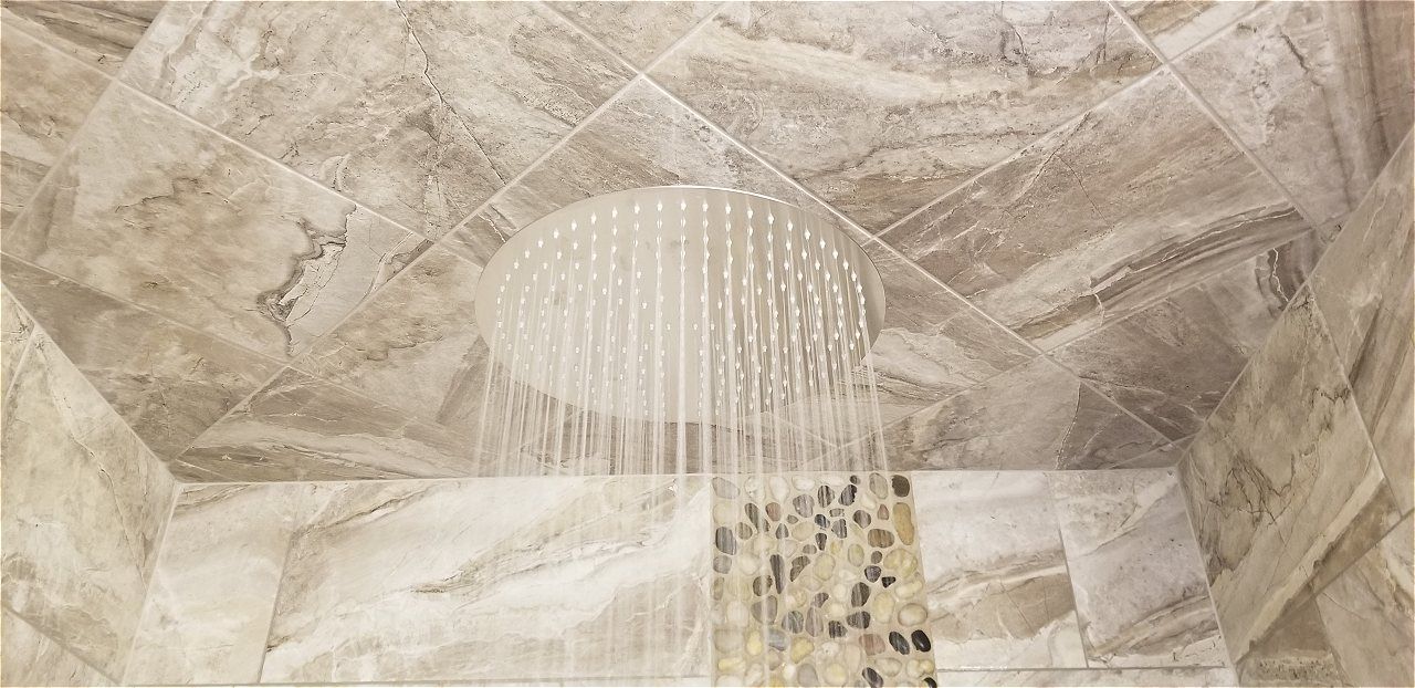 A Close Up Of A Shower Head In A Bathroom With Marble Tiles | Wichita, KS | David Lies Plumbing