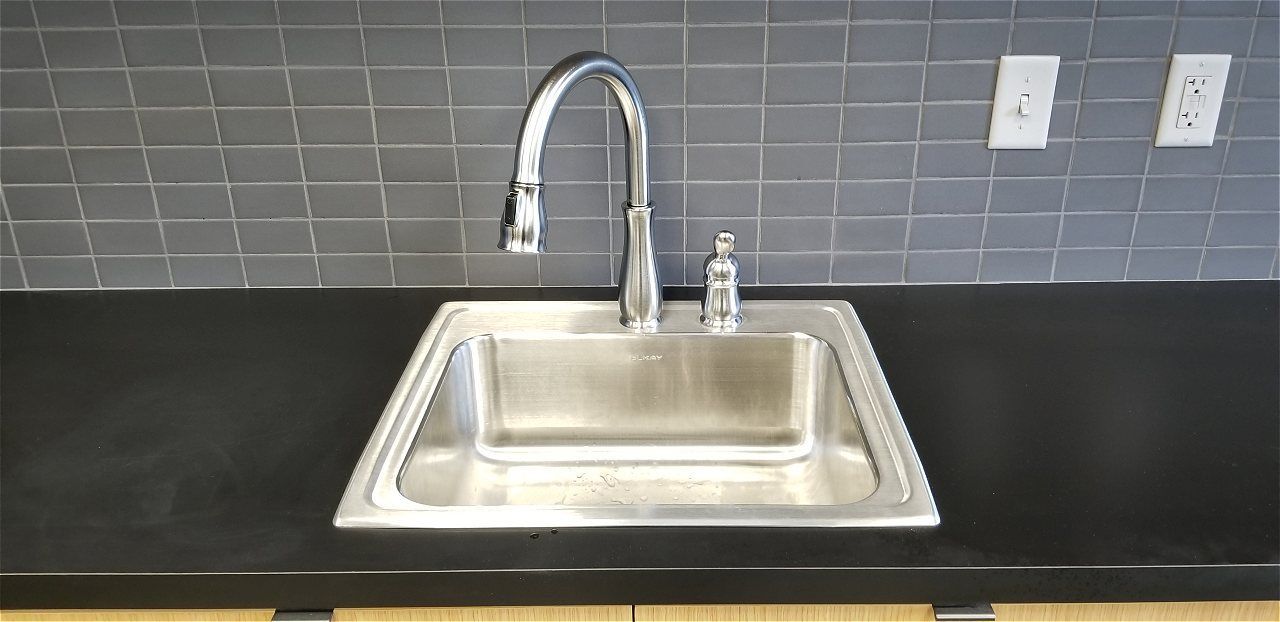 A Stainless Steel Kitchen Sink With A Faucet On A Black Counter Top | Wichita, KS | David Lies Plumbing