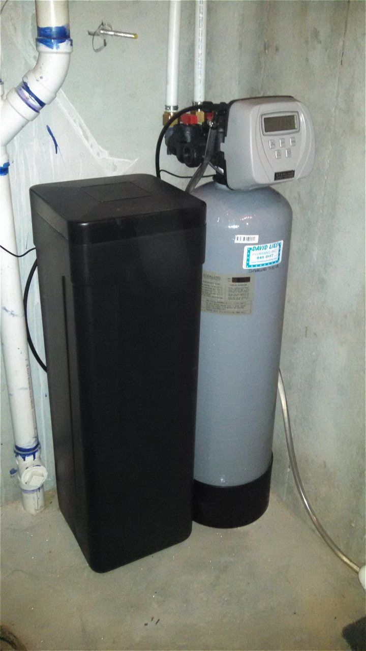 a water softener is sitting next to a black box in a basement .