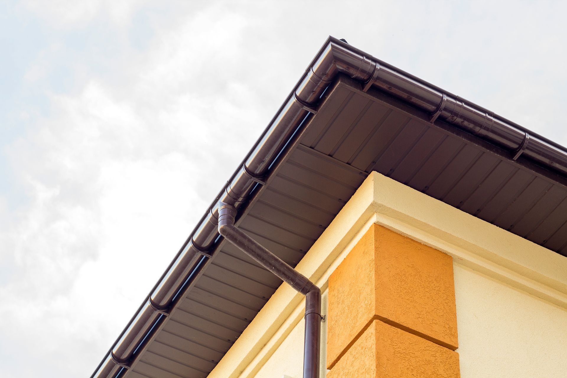 A close up of the roof of a house with a brown gutter.