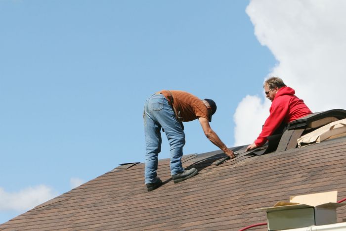 A man is working on the roof of a building at sunset