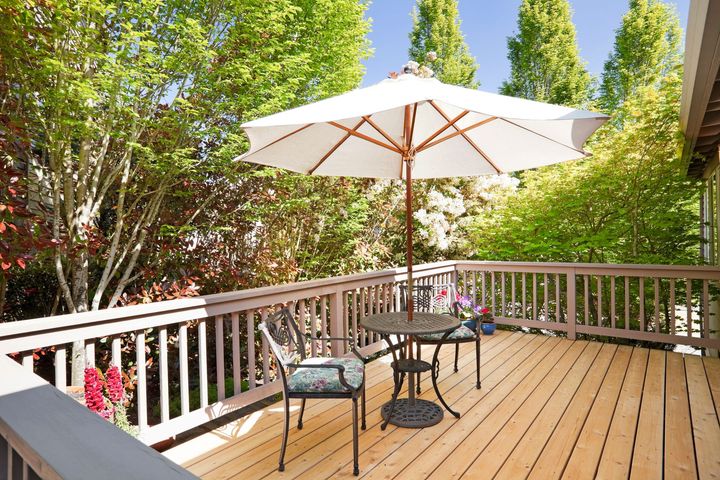 A wooden deck with two rocking chairs and mountains in the background.