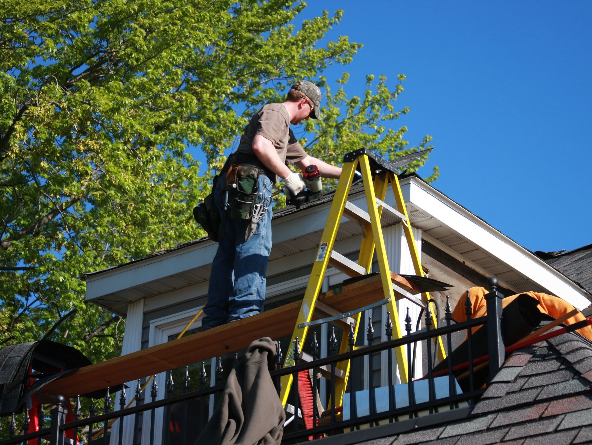 A man on a ladder working on the roof of a house