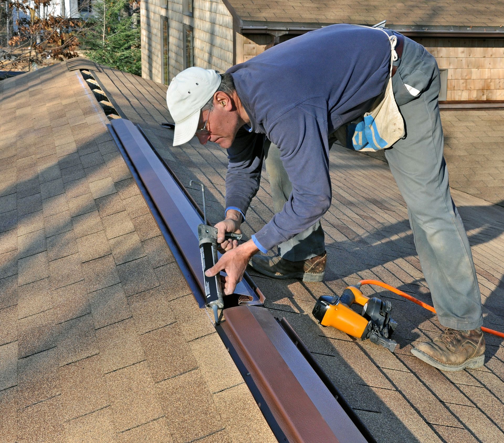 A man wearing a white hat is working on a roof