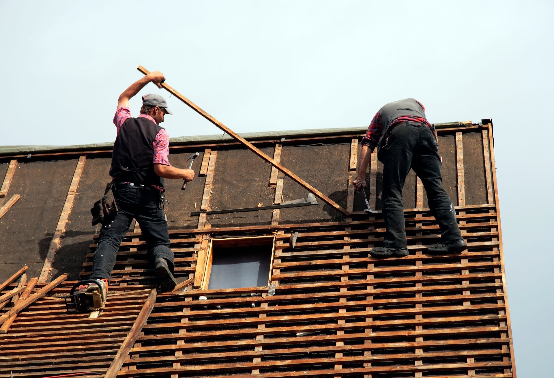 Two men are working on the roof of a building.