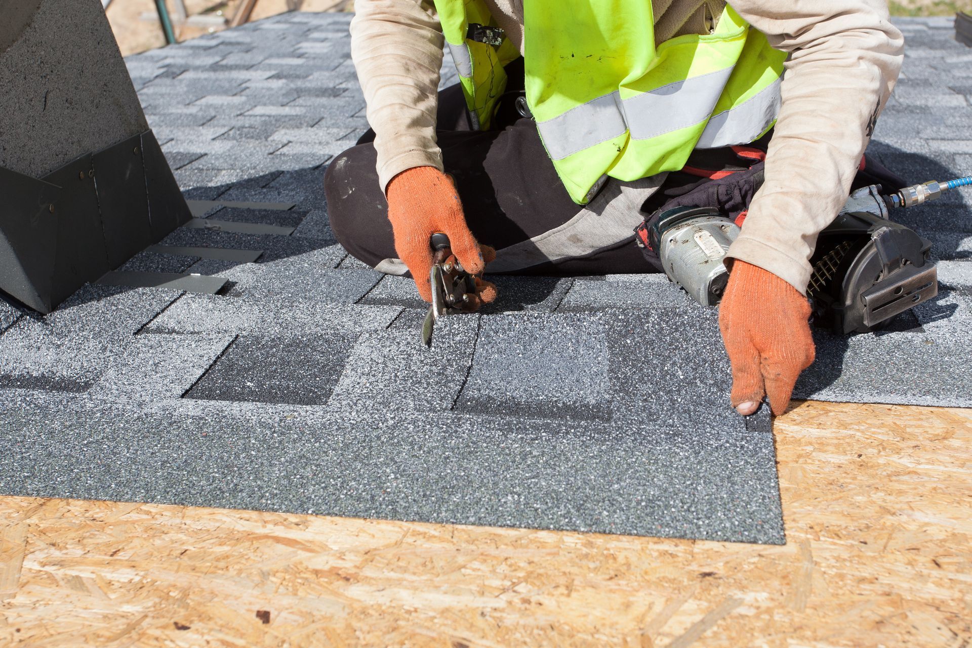 A man is laying shingles on a roof.