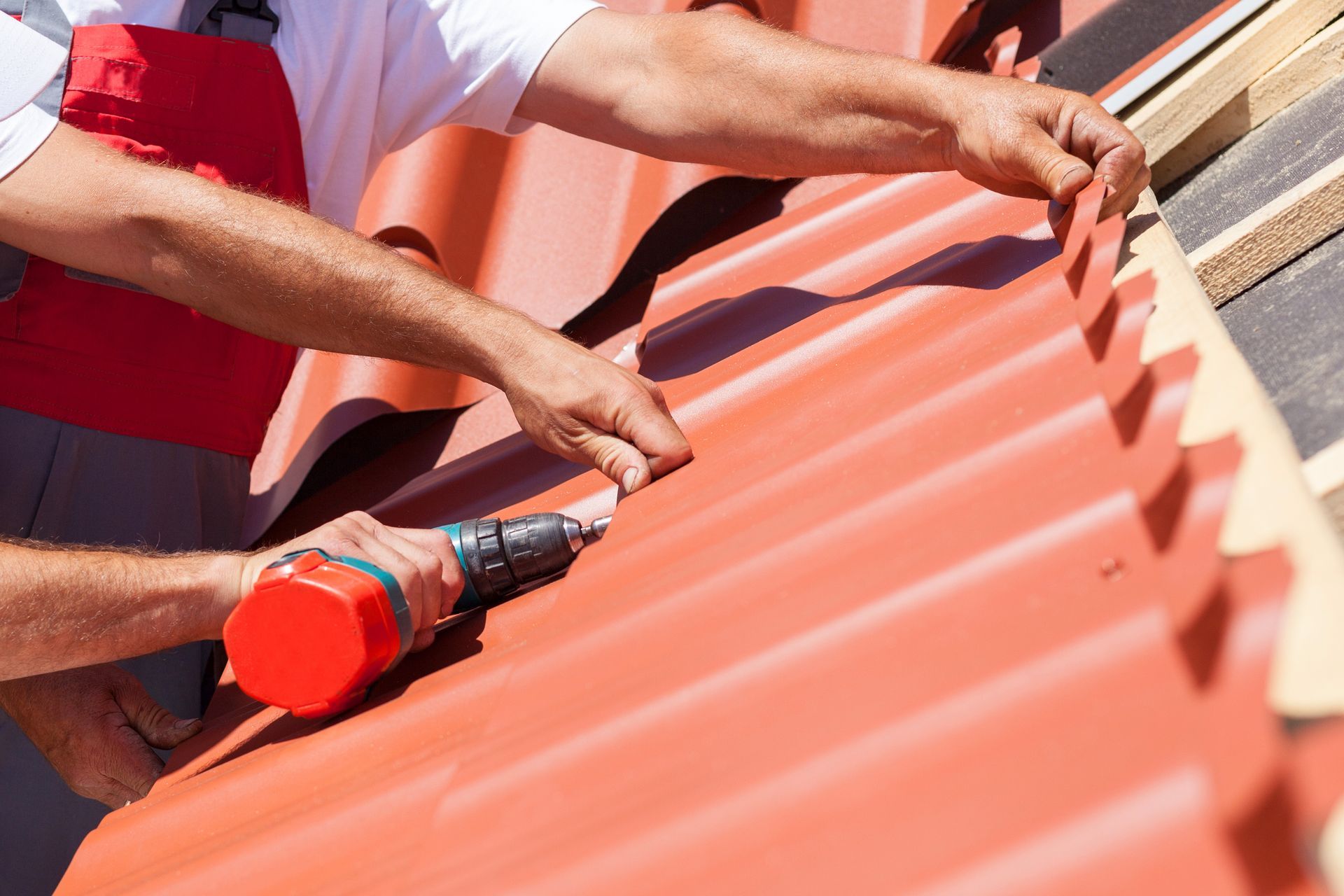 A couple of men are working on a red roof.