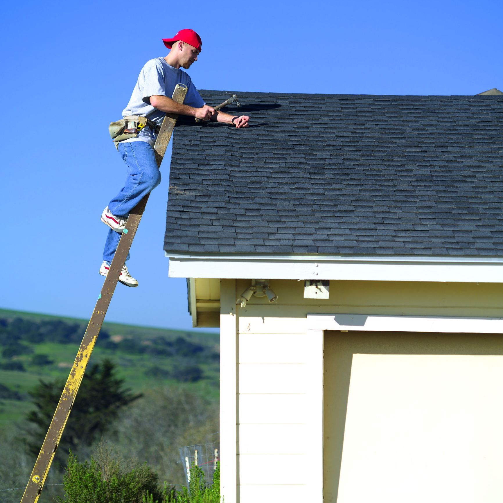 A man is standing on a ladder on top of a roof