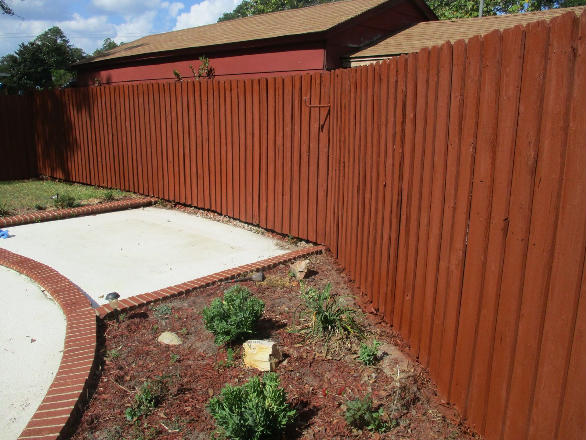 A wooden fence with a red house in the background