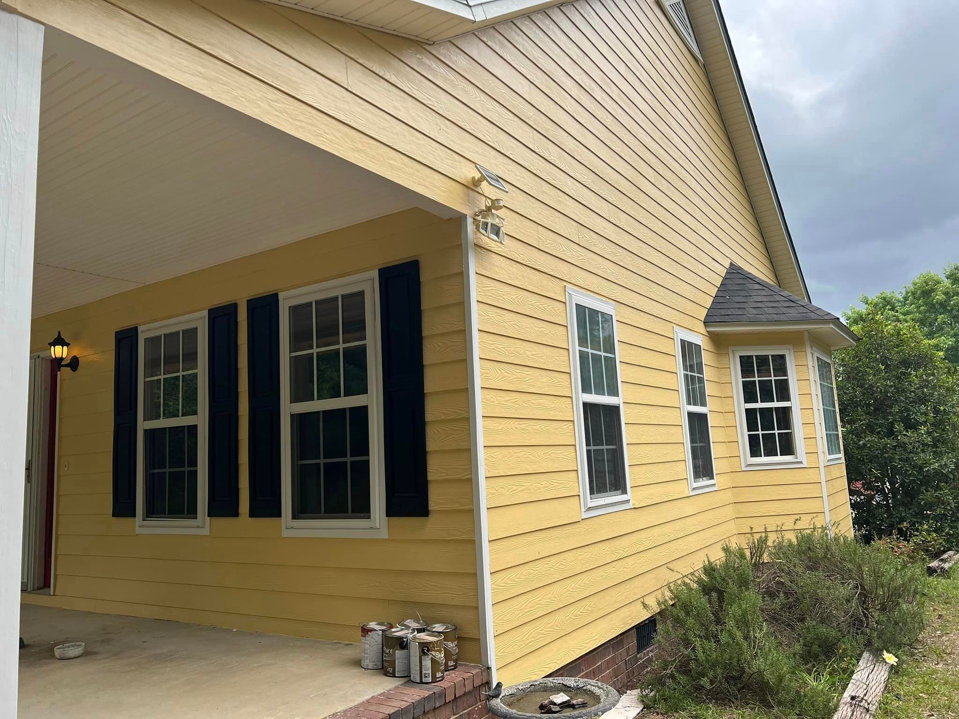 A yellow house with black shutters on the windows