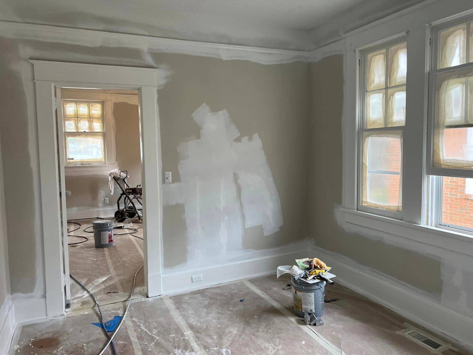 A room that is being painted with a bucket of paint on the floor