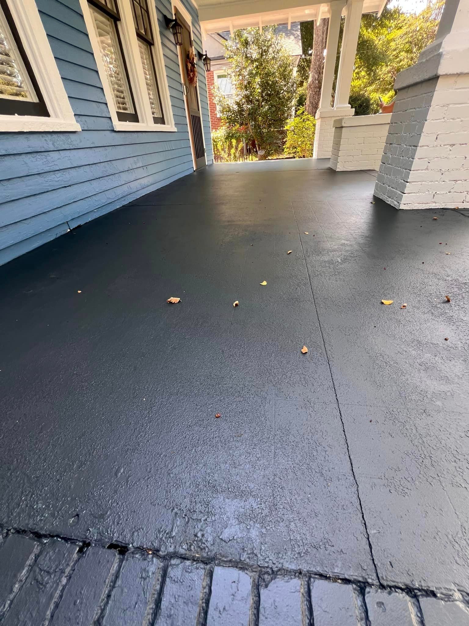 Blue painted porch with dark gray floor. Sunlight, brick, and house siding are visible.