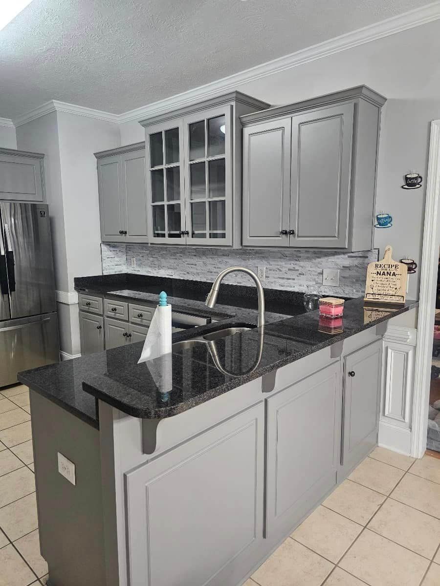 A kitchen with gray cabinets and black granite counter tops.