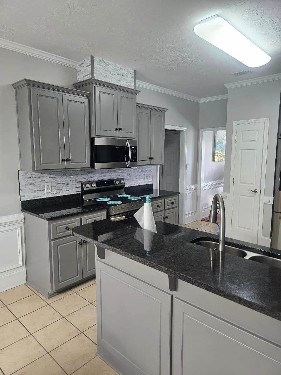A kitchen with gray cabinets and granite counter tops