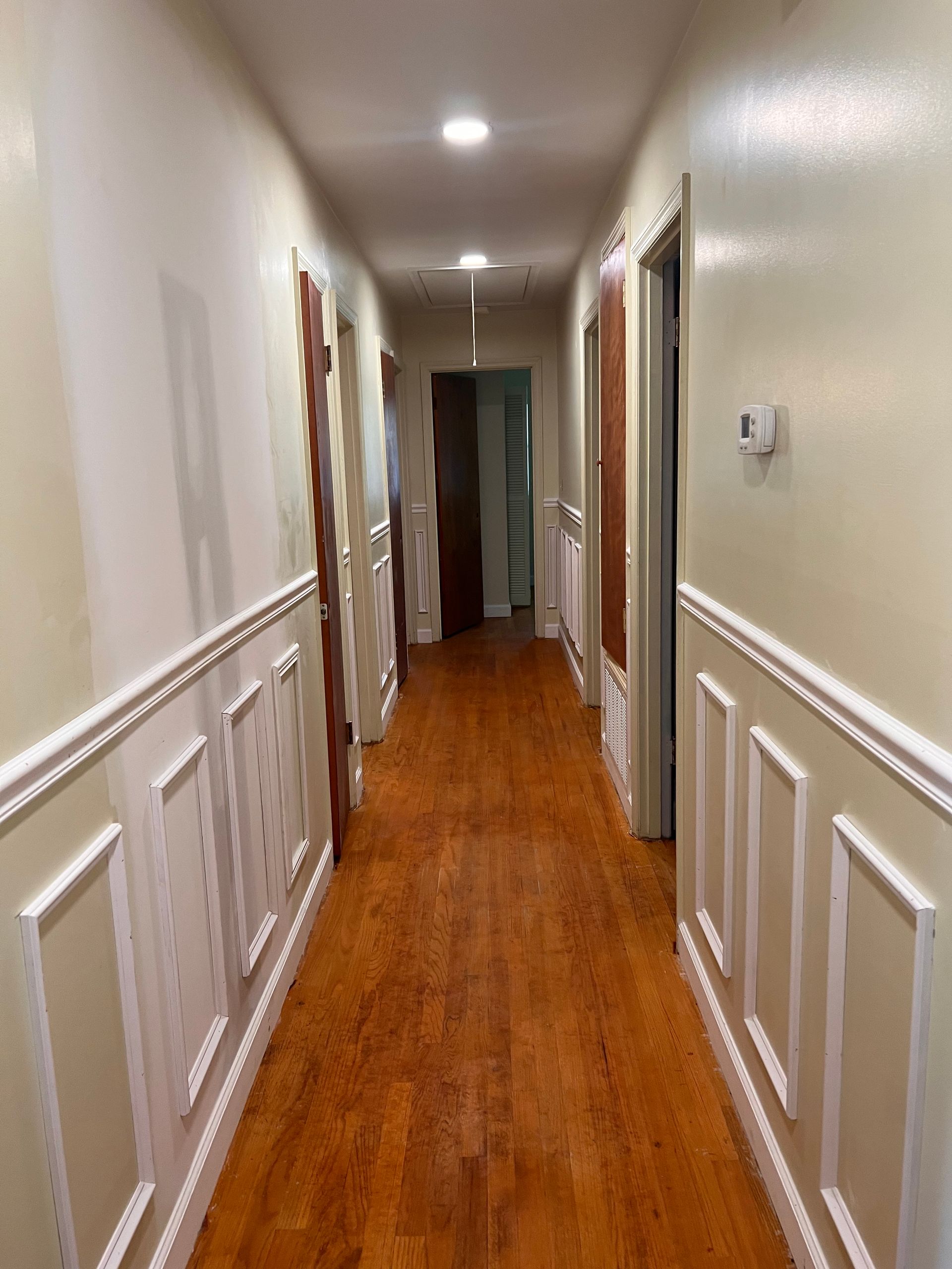 A long hallway with wooden floors and white trim