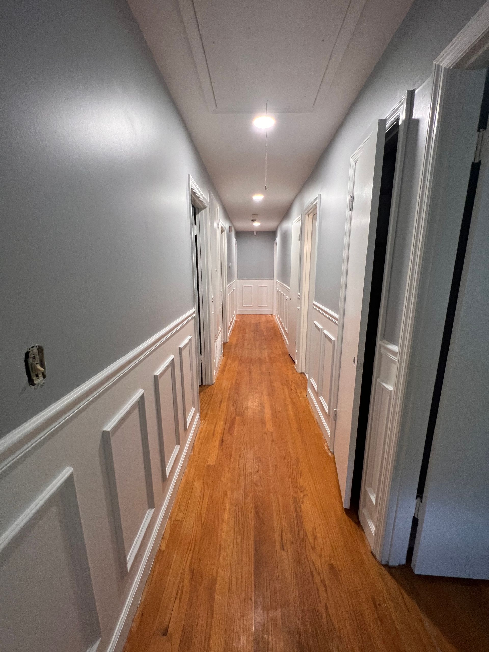 A long hallway with wooden floors and gray walls
