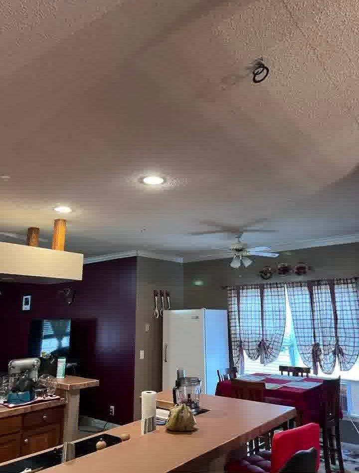 Interior kitchen with island and dining area; red-topped island, white fridge, dark cabinets.