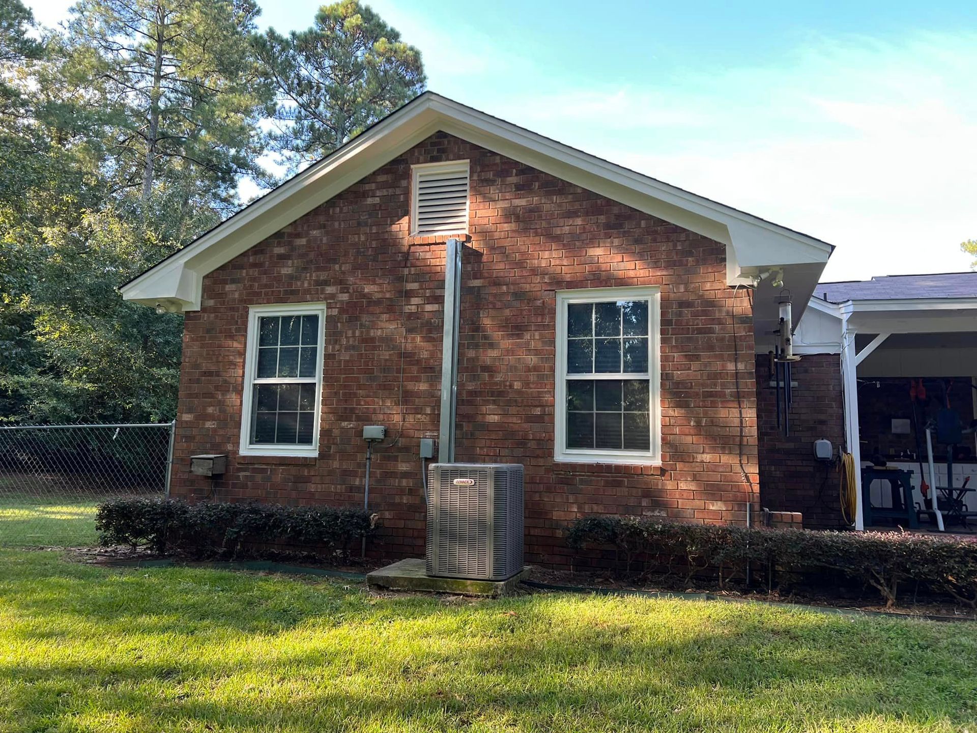 A brick house with a white roof and two windows