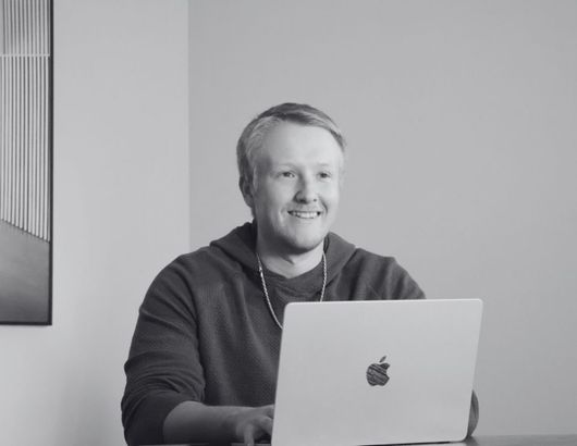 A man is sitting at a table with a laptop computer.
