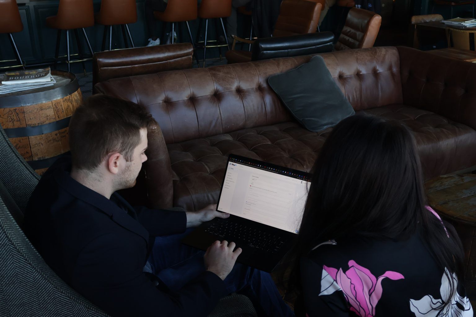 A man and a woman are sitting on a couch using laptops.