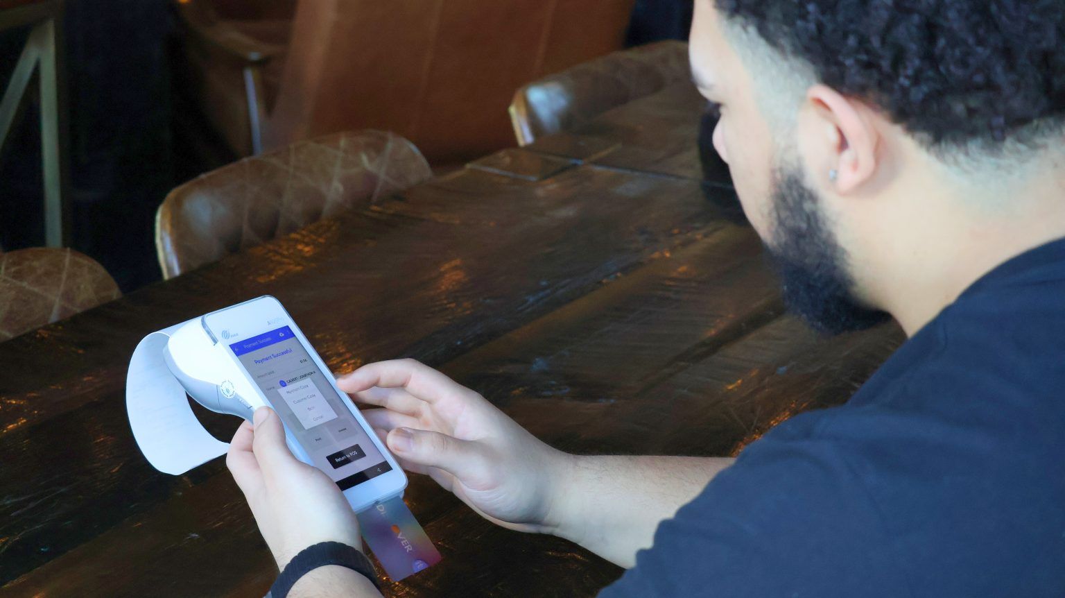 A man is sitting at a table using a cell phone.