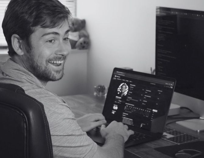 A man is smiling while using a laptop computer