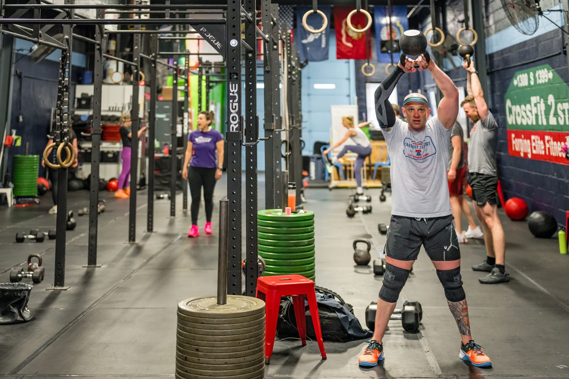 A man is holding a dumbbell over his head in a gym.